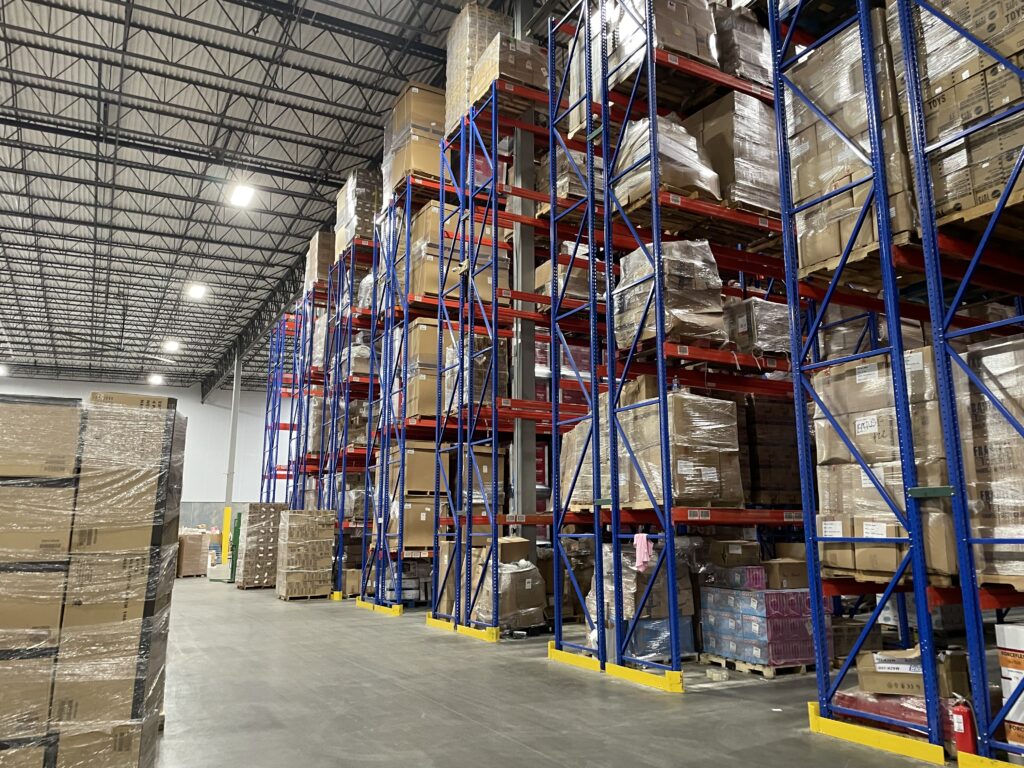 Rows of pallet racking in a 3PL logistics providers warehouse. On the pallet racking are pallets of Amazon Returns